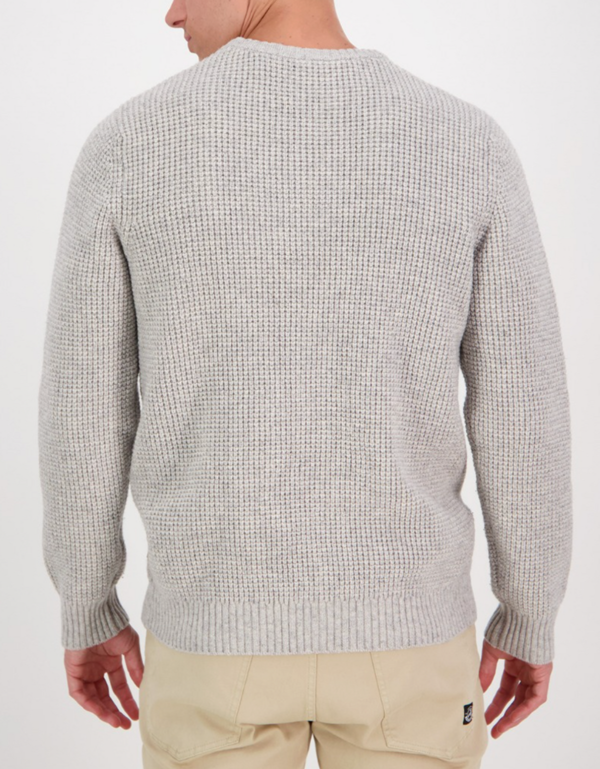The Swanndri Fistral Waffle Knit features a light gray, Lambswool construction with a cozy crew neck. The model is shown from the back, paired with beige pants against a plain white background.