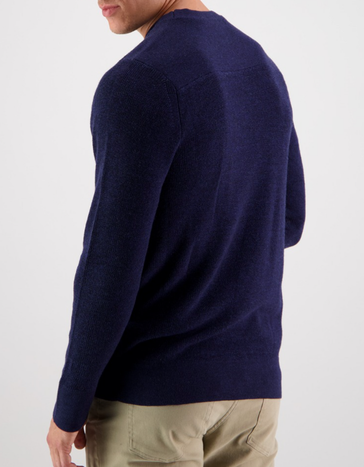 A person wearing a Swanndri Otahu River Crew Neck Merino Knit in dark blue and khaki pants is standing with their back to the camera against a plain white background.