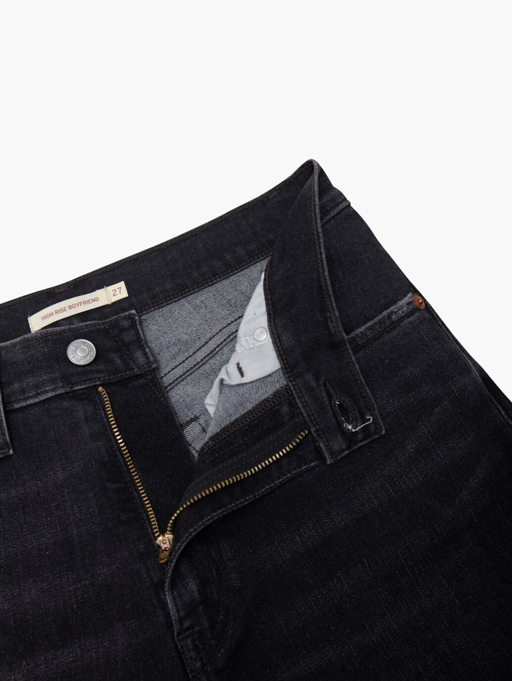 The Levis High-Waisted Boyfriend Jean in black has a partially open zipper and undone button, revealing a gray interior with a "27" label. The stretch denim texture highlights Levi's premium craftsmanship.