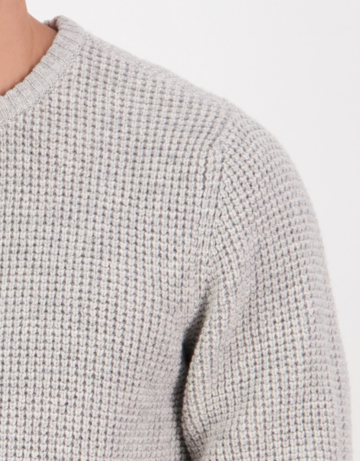Close-up of someone in a light gray Swanndri Fistral Waffle Knit sweater with a round neckline. The plain white background emphasizes the sweater's upper right side and cozy waffle knit design.