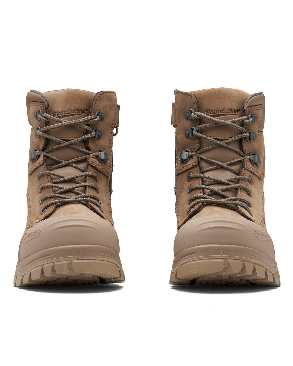 A pair of Blundstone 984 Zip Sided Scuff Cap Safety Boots with tan uppers, rugged soles, reinforced toes, and steel toe caps. These boots showcase a sturdy design featuring metal eyelets and thick laces for added durability. "Blundstone" is embossed on the tongue. The image presents a front view of both boots against a white background, highlighting their slip resistance.