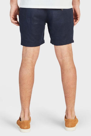 Rear view of a person wearing the Academy Brand Riviera Linen Short and tan slip-on shoes. The elastic waist ensures comfort as they stand against a plain white background, showcasing only their legs from the waist down.