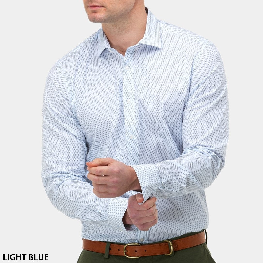 A person wearing a light blue Brooksfield Stretch Print Shirt with long sleeves and a subtle pattern is adjusting their cuffs. The stylish shirt is paired with green pants and a brown belt. The background is plain white, and the text "LIGHT BLUE" appears in the bottom left corner.