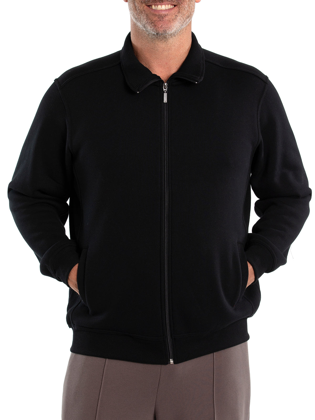A person wearing a black Breakaway Zed Snowy Mt Fleece Full Zip jacket has their hands in the pockets. They're also in grey cotton polyester pants. Only the torso is visible; their face isn't shown.