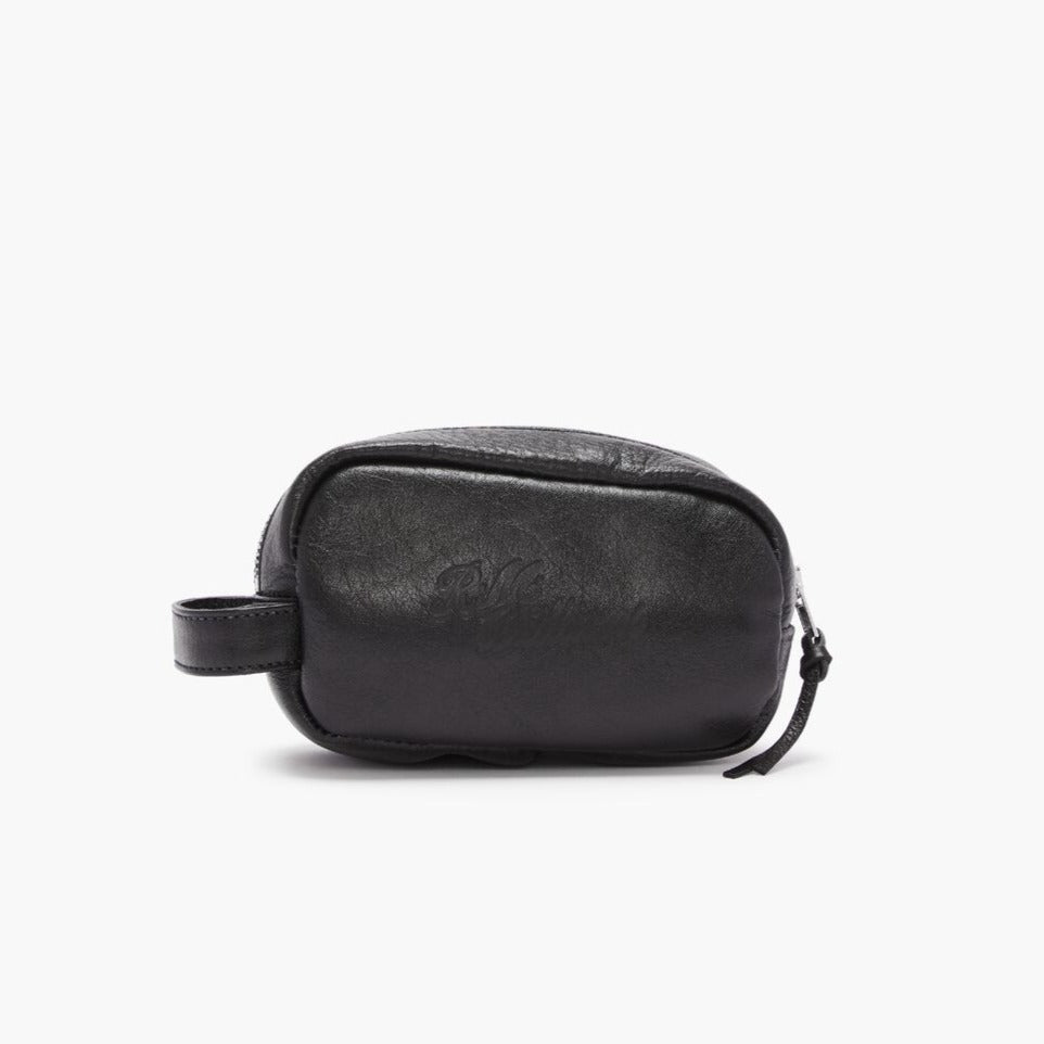 A small black full grain leather bag from RM Williams' Mini Travel Care Kit, featuring a smooth texture with subtle stitching details and a nearly invisible embossed logo on the front. It includes a zipper closure and a short strap on one end for easy carrying.
