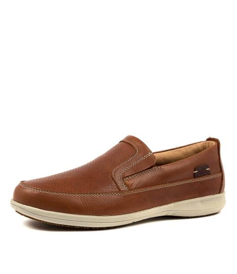 The Colorado Affleck Pull On Shoe is a brown leather slip-on featuring tan stitching, an off-white cushioned slip-resistant sole, and a decorative tab near the heel.