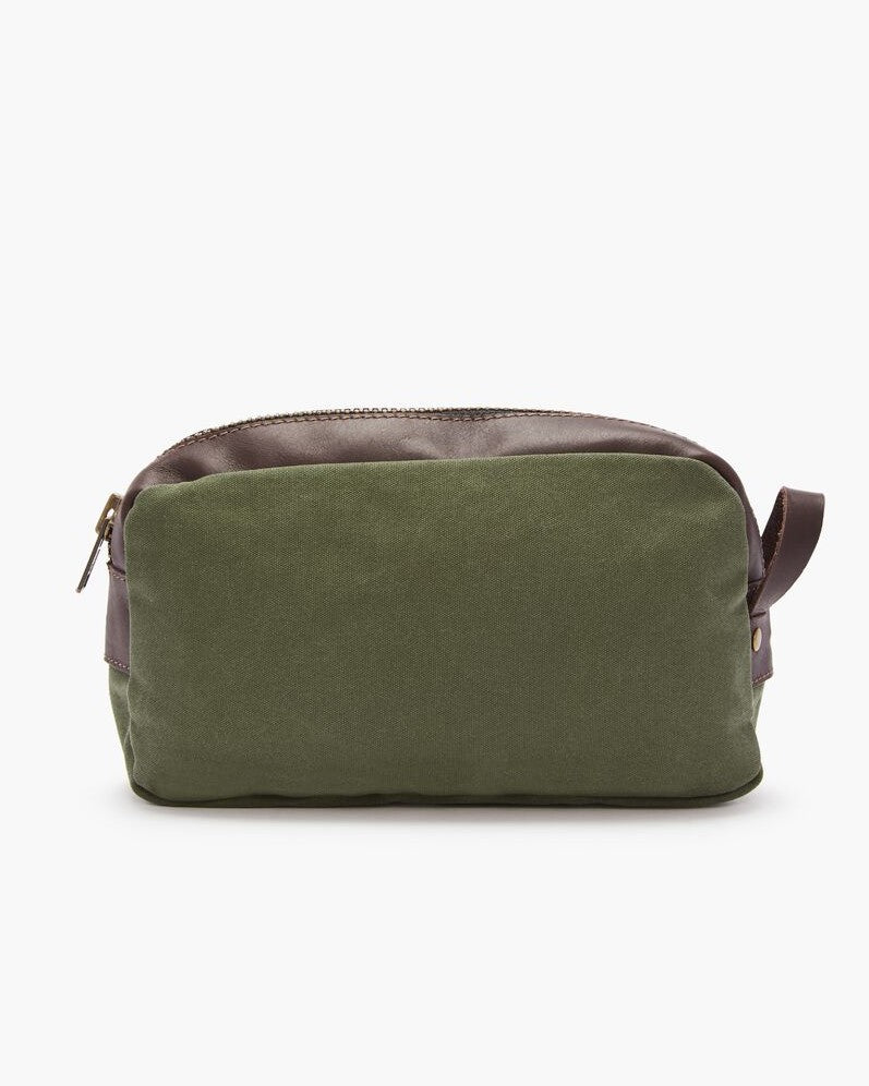 The RM Williams Ute Washbag is a rectangular olive green canvas bag with brown leather trims, a top zipper closure, and a small side handle, shown against a plain white background.