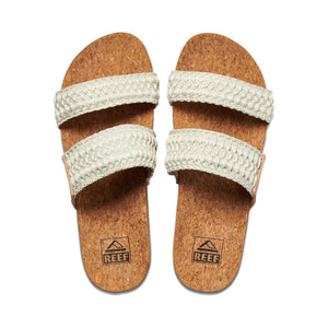 Two REEF Cushion Vista Thread sandals with cork soles display the brand logo, featuring two wide cream-colored woven straps and cushioned EVA foam, are shown side by side on a white background.