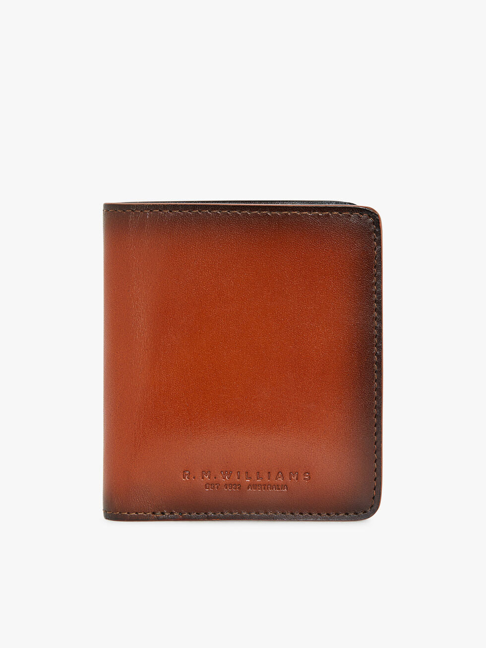 The RM Williams Urban Bi-Fold wallet in brown full grain leather features subtle stitching and "R.M. WILLIAMS EST 1932 AUSTRALIA" embossed on the front, displayed on a plain white background.