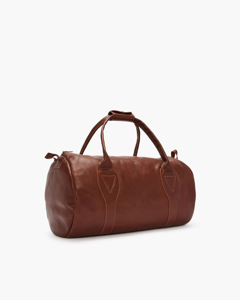 The RM Williams Leather Ute Bag is a brown, Australian Made cylindrical bag with two handles, zipper closure, visible stitching, and is shown on a white background.