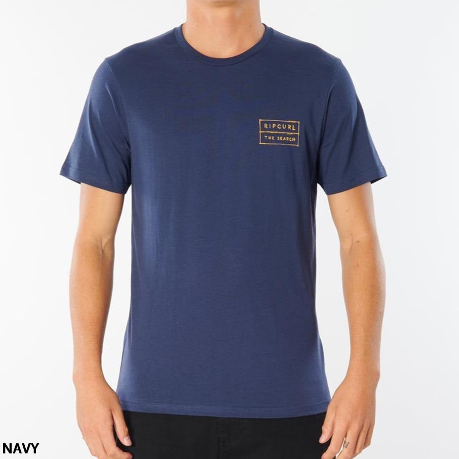 A person wearing the navy Rip Curl 50/50 Scratch Tee made of 100% cotton, featuring a small rectangular logo on the left chest area with the text "Rip Curl" and "The Search." The comfortable t-shirt is showcased as the person faces forward against a plain white background, with "NAVY" written in the bottom left corner.