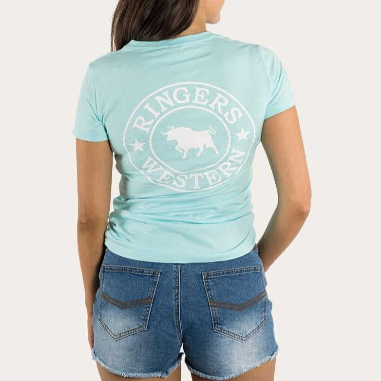 A person stands with their back to the camera, wearing a comfortable Ringers Western Womens Signature Bull Classic Fitted T-Shirt made of 100% cotton and denim shorts. The light blue t-shirt features a white buffalo and stars logo.
