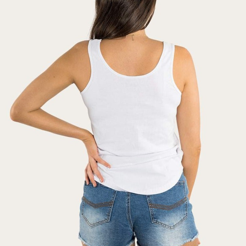 A person stands facing away, wearing the Ringers Western Rodeo Women's Scoop Neck Tank in white with a sleeveless design and blue denim shorts. Their right hand rests on their hip, and their long, dark hair flows down their back against a plain, light-colored background.