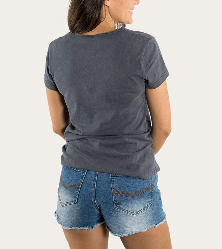 A person with long hair wears a relaxed gray tee, the Ringers Western Rodeo Women's V Neck, made from 100% cotton, paired with denim shorts, standing back to the camera against a plain background.
