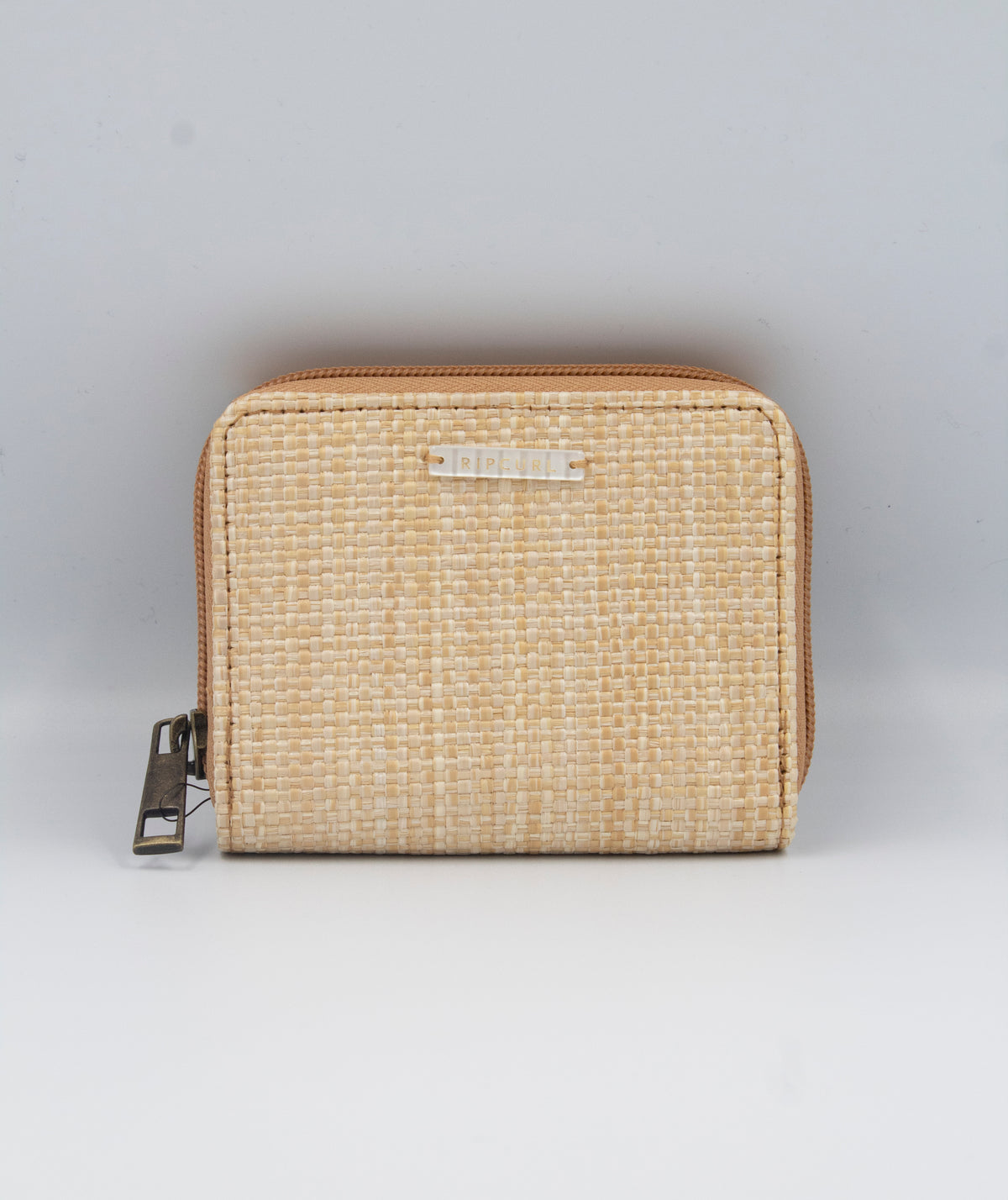 A Rip Curl Sunset Palms mid-sized wallet, rectangular and beige with a woven texture, is centered on a light gray background. It features a left-sided zipper closure and a front metallic brand plate.