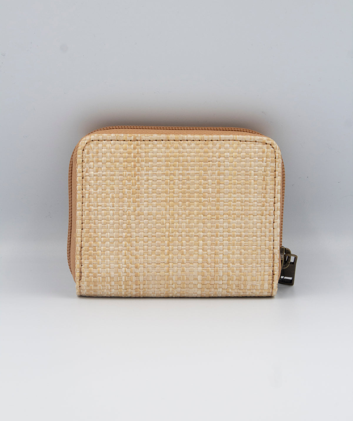 A beige Rip Curl Sunset Palms Mid Sized Wallet is shown on a light gray background. It features a zip-around closure with a metallic zipper pull on the right side, and its textured material offers an elegant and minimalist look.