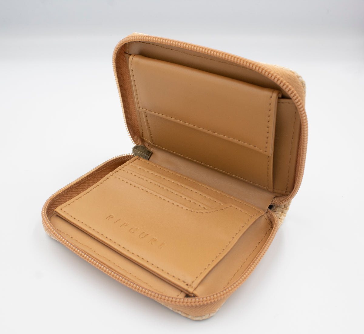 The Rip Curl Sunset Palms mid-sized wallet, crafted from tan leather, features a zipper, card slots, and a bill compartment. The brand name is embossed on an inner panel. Displayed against a plain white background, it blends style with practicality.