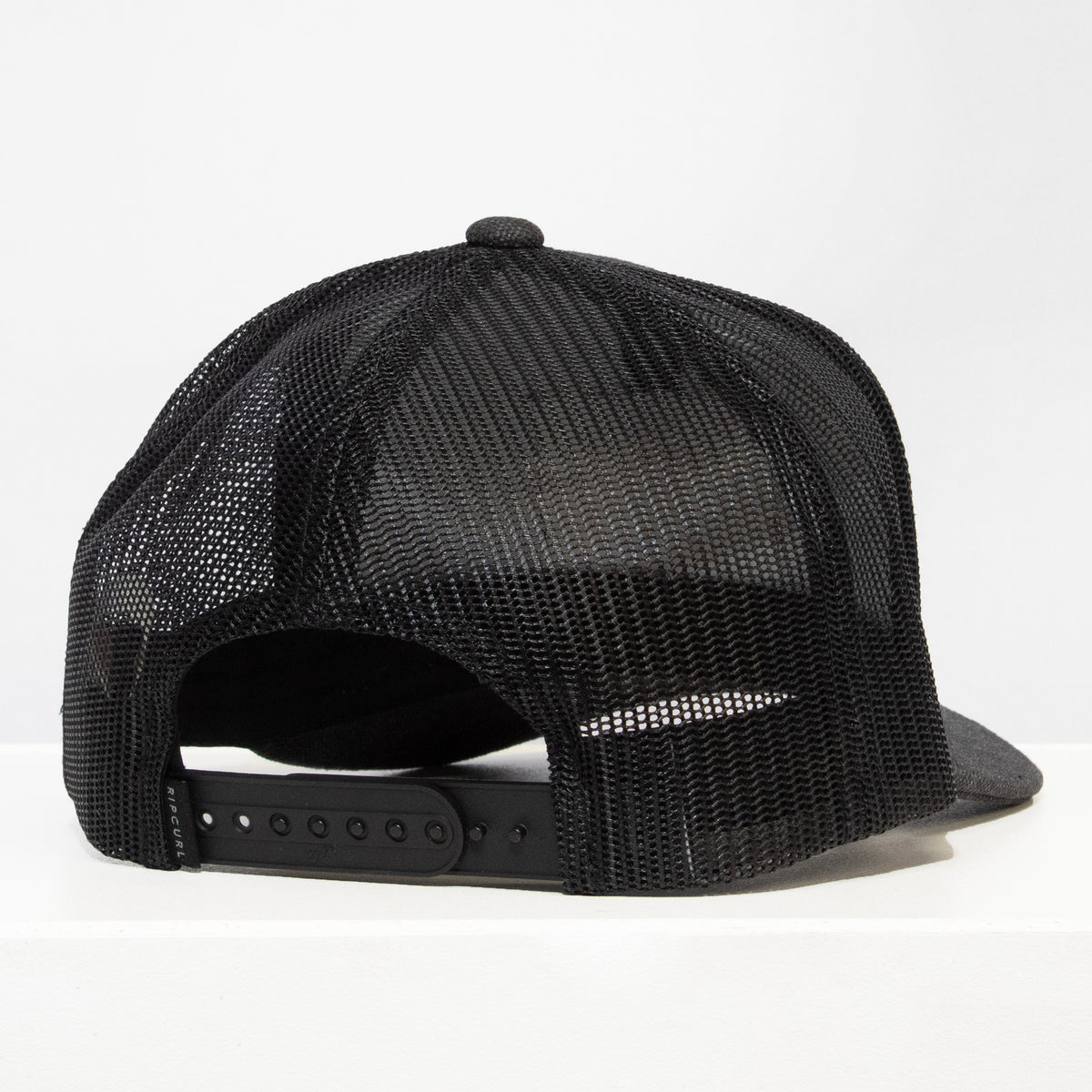 A black Rip Curl Surf Revival Curve Trucker hat is shown from the back on a flat white surface, featuring an adjustable snapback closure.
