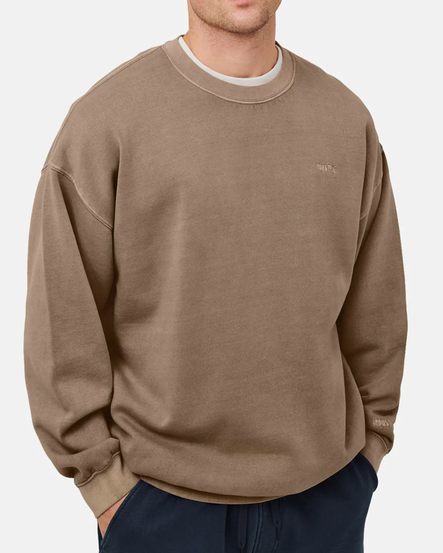 A person in the brown "Industrie The Del Sur Sweat" with fleece lining and small embroidered logos on the chest and right sleeve stands against a white background. They are wearing dark pants, but their head is partially out of frame.