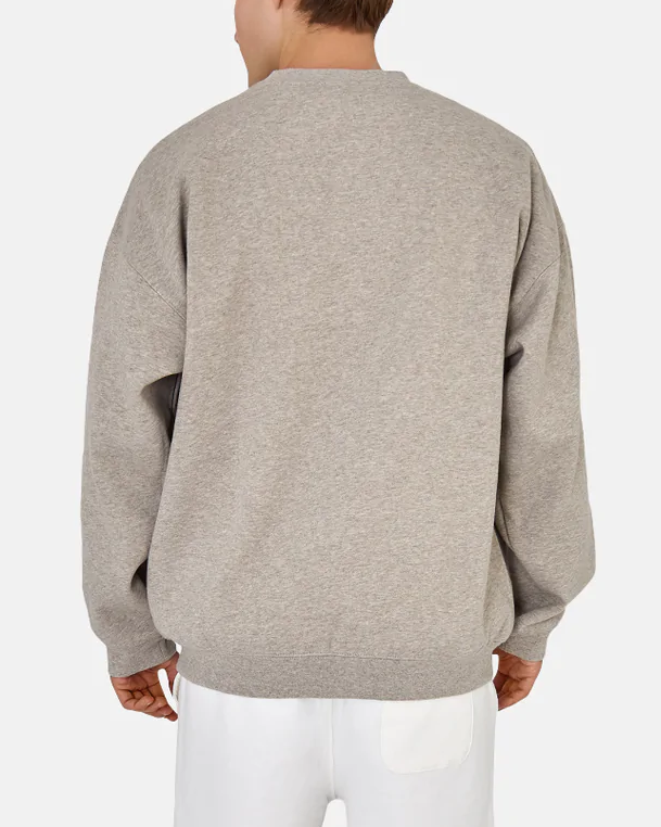 Someone faces away from the camera, wearing Industrie The Del Sur Sweat in an acid wash with an oversized fit and long sleeves. They're paired with white pants against a plain white background, highlighting the jumper's comfort.