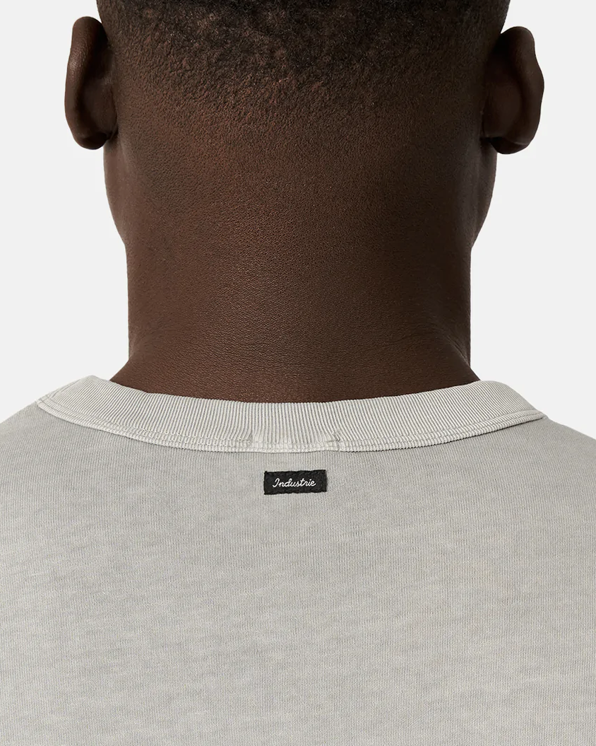 Close-up of the back of a person’s neck and shoulders, wearing the Industrie The Del Sur Tee in light gray with a small black "Indispensable" collar label. The relaxed, oversized fit stands out against a plain white background.