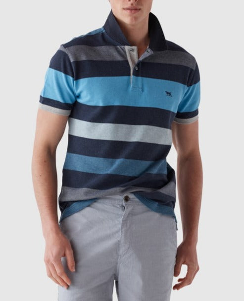 A person is wearing a short-sleeved, comfortable Rodd & Gunn Lake Moeraki Sports Fit Polo with horizontal stripes in shades of blue and gray, paired with light gray pants. The cotton polo boasts a small logo on the chest. The person's face is not shown in the image.