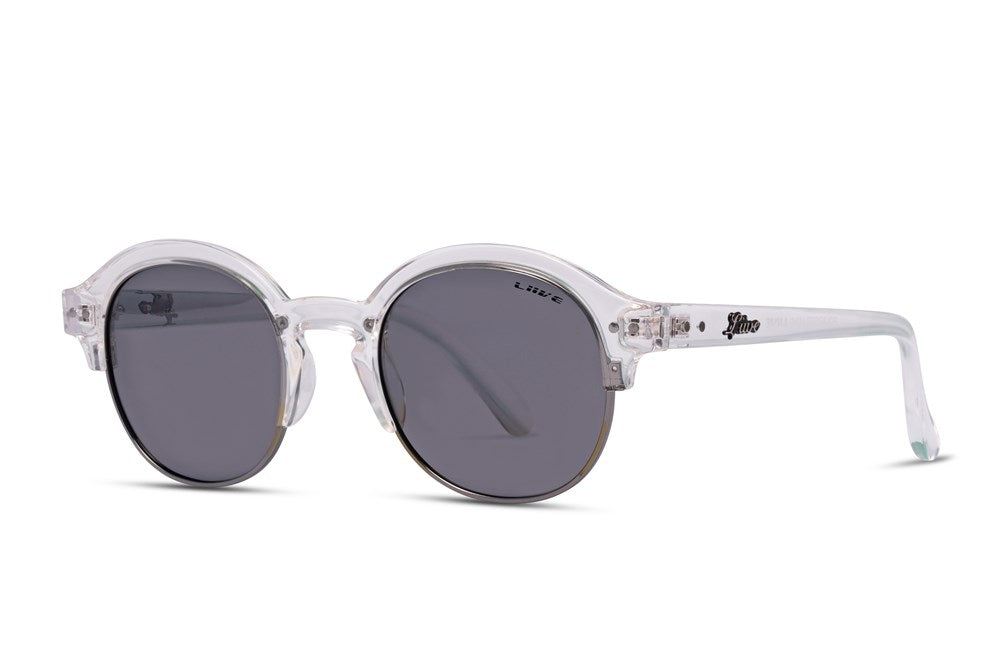 A pair of Liive Canggu Polar Sunglasses featuring round, polarised grey lenses and clear, translucent frames. The design is minimal and modern, with the brand name "Blenders" visible on one of the arms, offering UV protection for your eyes.