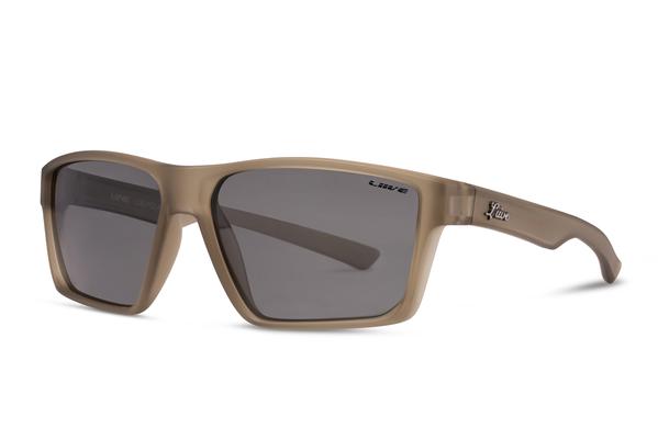 The Liive Lob Polar Sunglasses feature a pair of matte beige, rectangular frames with dark tinted lenses. Constructed from lightweight polycarbonate for durability, these sporty and contemporary sunglasses have the added detail of a small engraved logo on the left temple arm.
