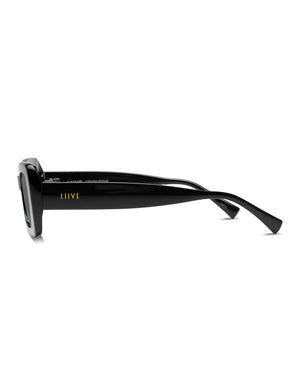 The Liive Crush Sunglasses are featured in a side view, showcasing their sleek black frames with a glossy finish. The brand name "Liive" is displayed in small yellow letters on the temple arm. These sunglasses provide UV protection and have a modern, minimalist design with slightly curved arms.