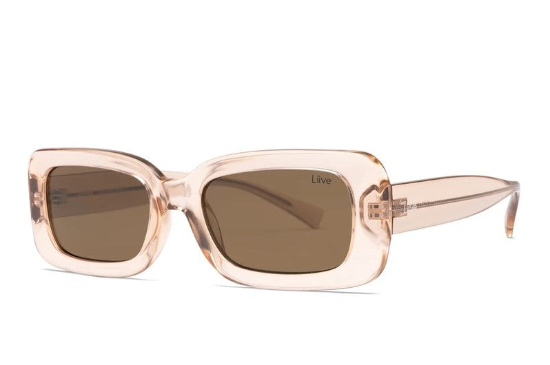 The Liive Crush Sunglasses feature rectangular frames in a transparent peach color with dark smoke lenses. Made from lightweight polycarbonate for comfort and UV protection, they are displayed front-on against a white background.