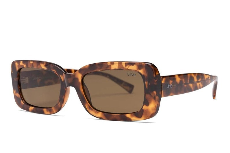 Liive Crush Sunglasses feature a tortoiseshell rectangular design with dark polycarbonate lenses offering UV protection. The glossy frame has a marbled brown pattern, and the arms subtly display the logo.