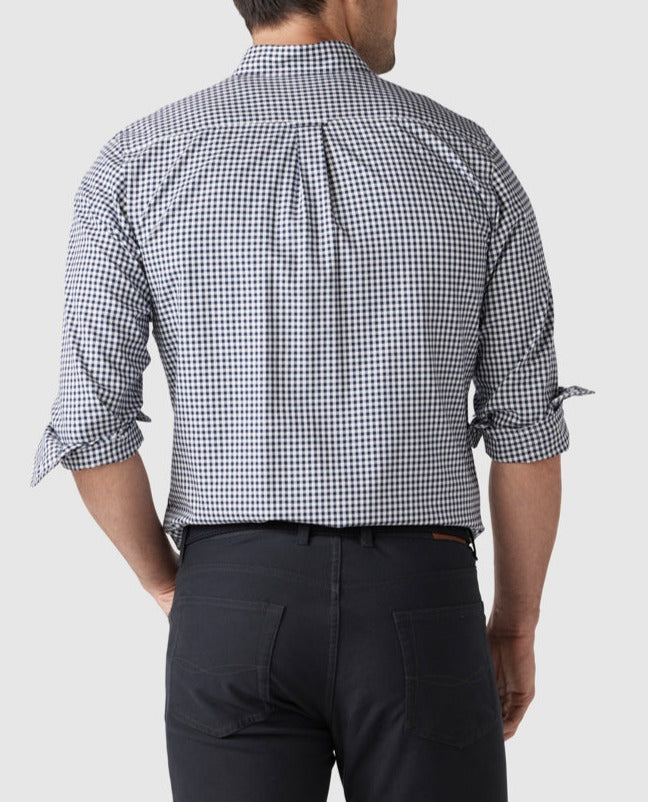 A man is seen from behind wearing a stylish Rodd & Gunn Gunn Check Oxford Sports Fit Shirt, featuring a black and white checkered pattern. The 100% cotton shirt has rolled-up sleeves. He pairs it with dark pants against a plain white background.