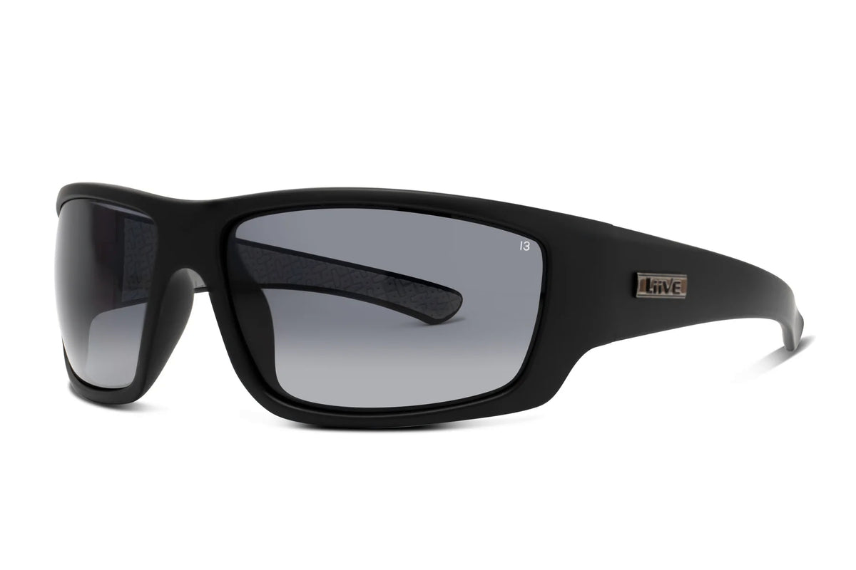 Liive Z Hammer Safety Sunglasses feature a sleek design with rectangular, shatterproof gray-tinted lenses and a thick frame offering UV protection. A small rectangular logo on the side enhances their stylish yet practical appeal.