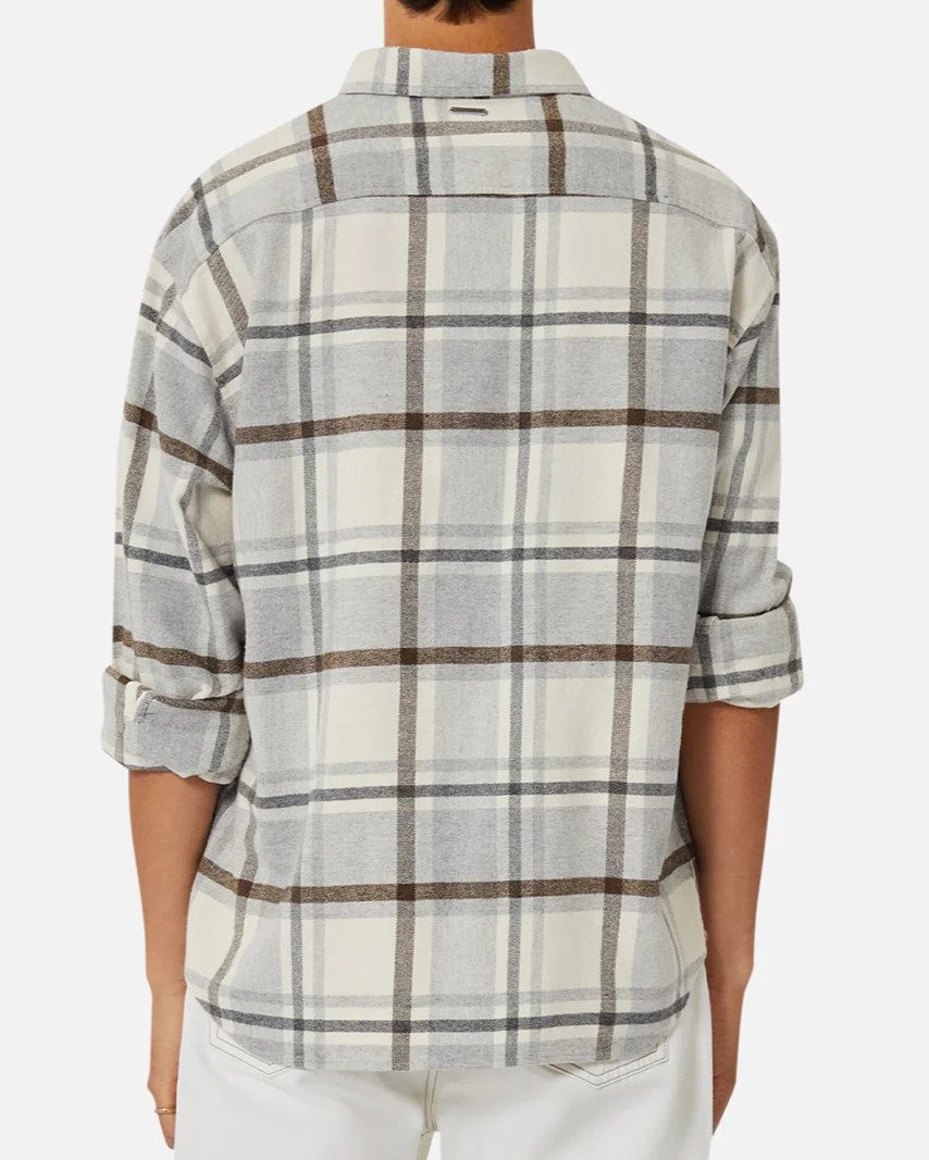 A person stands against a plain white background, wearing the Industrie The Elmhurst Shirt, a cream and gray plaid overshirt in brushed cotton. The sleeves are partially rolled up, enhancing its relaxed fit.