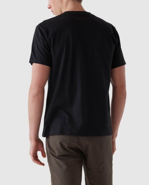 A person is seen from the back, wearing a plain black Rodd & Gunn The Gunn T-Shirt and khaki pants. The background is a solid light grey color, highlighting the sports fit of the high-quality Australian Cotton T-shirt.