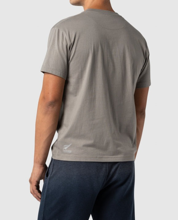 A person showcases the comfortable Rodd & Gunn Cumulus Sports Fit Tee in premium gray cotton, paired with dark pants. A small logo adorns the lower right side. Set against a plain light gray background, this look embodies effortless style.