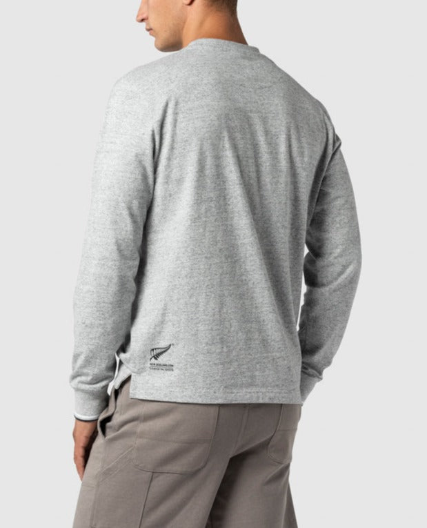 A person in a light gray Rodd & Gunn Bonny Glen Sports Fit T-Shirt and khaki pants faces away. The 100% cotton shirt has a logo on the lower back, against a plain white background.