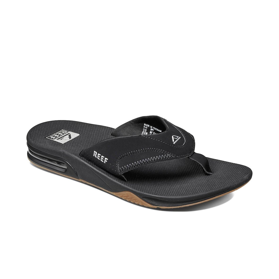 The REEF Fanning is a black sandal with textured soles and thick synthetic stitched straps, featuring the brand name and logo. It has an EVA footbed, a brown undersole, and visible heel cushioning.