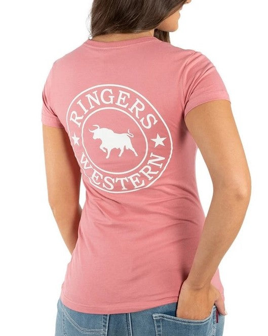 A person is facing away, highlighting the back of their Ringers Western Womens Signature Bull Classic Fitted T-Shirt. The comfortable and casual pink t-shirt, made from 100% cotton, features a large white logo depicting a bull and the text "Ringers Western." It complements their long hair and blue denim jeans as they casually rest their left hand in their back pocket.
