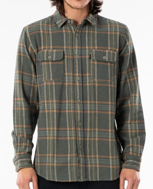 A person is wearing the Rip Curl Griffin Flannel Shirt, a long-sleeved, button-up shirt made from soft brushed cotton with a green, orange, and grey plaid pattern. The shirt features two chest pockets with buttoned flaps and the background is plain white. The person's face is not visible in the image.