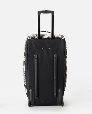 The Rip Curl Jupiter 80L Paradise Travel Bag, featuring a black design adorned with a floral pattern on the sides, is shown standing on its wheels with an extended telescopic handle—the perfect travel companion.