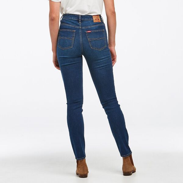 Rear view of a person wearing the Riders Classic High Slim Jean, paired with a crisp white shirt and brown ankle boots, standing confidently with legs slightly apart against a plain white background.
