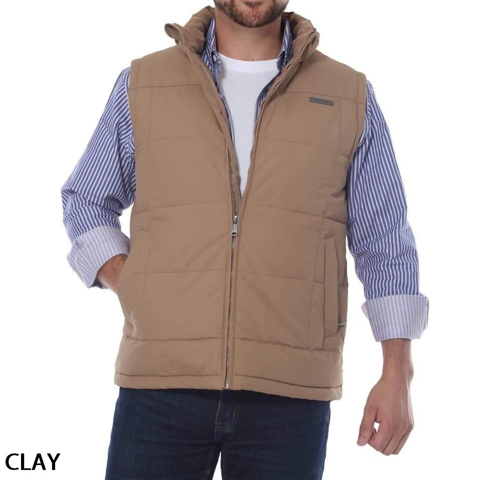 A man is wearing a Ringers Western Horsham Puffer Vest in tan, which has a soft fleece lining, over a white shirt with blue and white striped long sleeves. The vest, unzipped for a relaxed look, features an adjustable waist, and he has one hand in his pocket. The word "CLAY" is written in the bottom left corner.