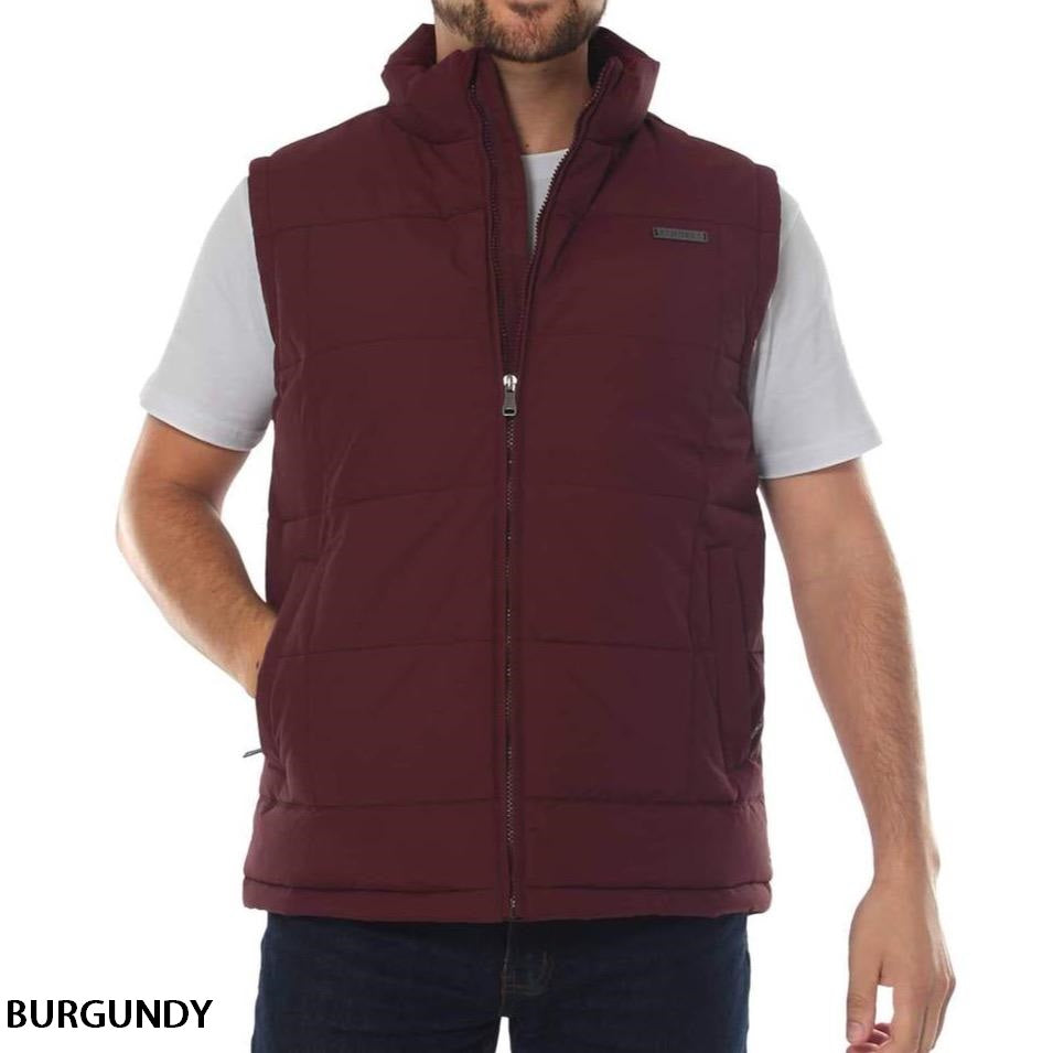 A man is wearing the Ringers Western Horsham Puffer Vest, a sleeveless, puffy, burgundy vest over a white t-shirt. The vest, zipped up and with a high collar, features an adjustable waist and soft fleece lining for added comfort. He stands with his left hand in his pocket against a plain white background. The word "BURGUNDY" is written at the bottom left corner.