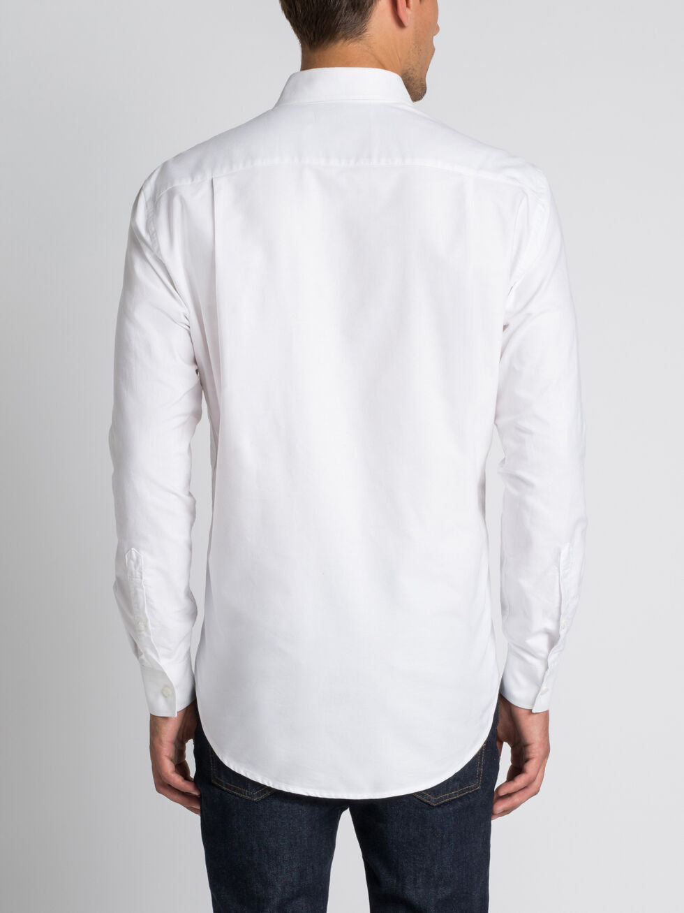 A man is seen from behind wearing the RM Williams Collins Shirt in white with dark jeans, standing against a plain light background.