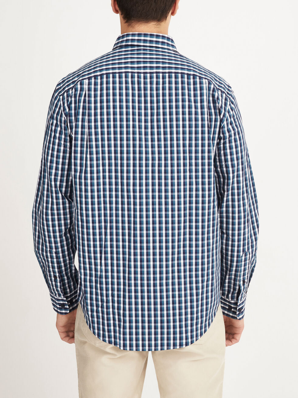 A person is seen from behind, wearing the RM Williams Collins Shirt—a blue, white, and black checkered long-sleeved 100% cotton shirt—with light-colored pants against a plain white background.