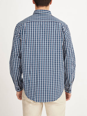 A person is seen from behind, wearing the RM Williams Collins Shirt—a blue, white, and black checkered long-sleeved 100% cotton shirt—with light-colored pants against a plain white background.