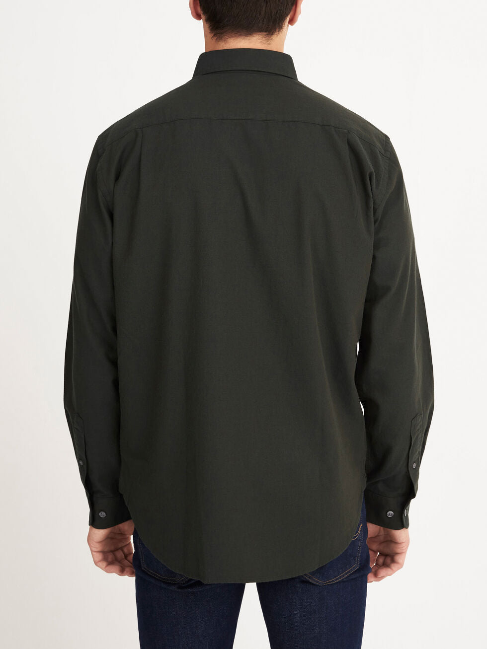 A man faces away from the camera, wearing a long-sleeved dark green RM Williams Collins Shirt and dark blue jeans, standing against a plain white background.