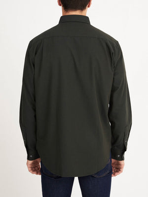 A man faces away from the camera, wearing a long-sleeved dark green RM Williams Collins Shirt and dark blue jeans, standing against a plain white background.