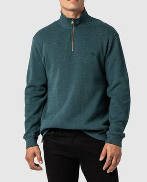 A person is wearing a stylish Rodd & Gunn Alton Ave Sweat in teal, featuring a quarter-zip design, high collar, and small logo on the left chest, paired with black pants. The background is plain light gray.